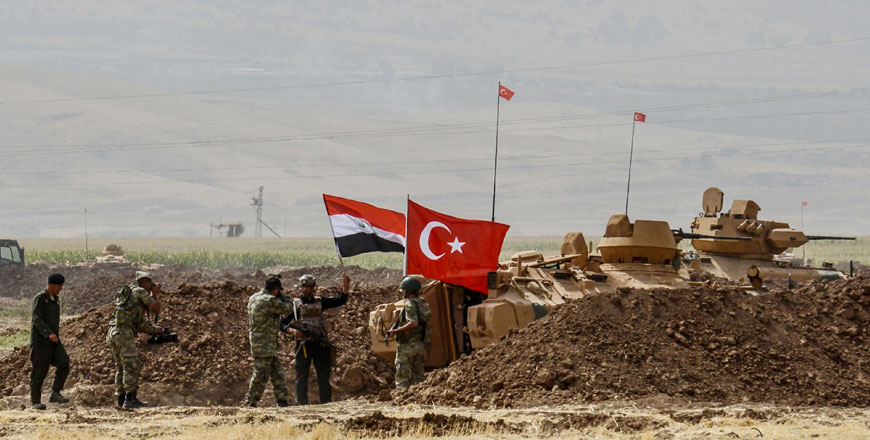 A photographer takes photos as soldiers stand next to tanks bearing Turkish and Iraqi flags during a joint military exercise near the Turkish-Iraqi border on Tuesday (AFP photo)