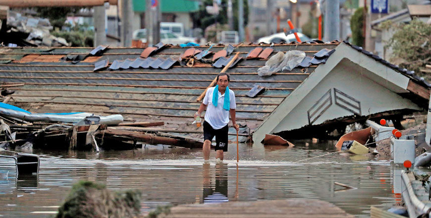 A local resident walks in front of submerged and destroyed houses in a flooded area in Mabi town in Kurashiki, Okayama prefecture, Japan, on Sunday (Reuters photo)