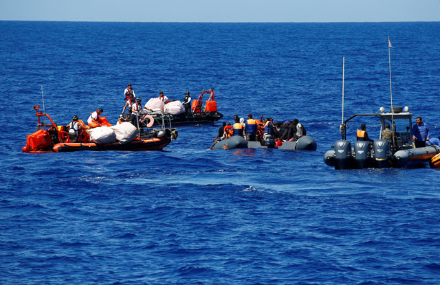 Migrants on a rubber boat are rescued by the SOS Mediterranee organisation during a search and rescue  operation, as the Libyan Coast Guard (right) patrols in the Mediterranean Sea, off the Libyan Coast, on September 14 (Reuters photo)
