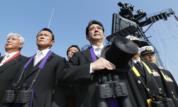 In this October 18, 2015 file photo, Japanese Prime Minister Shinzo Abe (centre) stands with Deputy Prime Minister and Finance Minister Taro Aso (second left) and Defence Minister Gen. Nakatani (left) during the official triennial Maritime Self-Defence Force fleet review aboard an escort ship in the waters off Sagami Bay, south of Tokyo (AP photo)