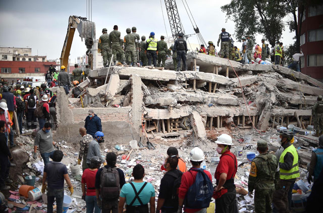 Rescuers, firefighters, policemen, soldiers and volunteers search for survivors in a flattened building in Mexico City on Wednesday after a strong quake hit central Mexico killing at least 217 people (AFP photo)