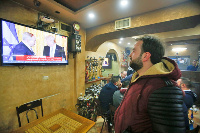 A Palestinian man watches a joint press conference by US President Donald Trump and Israeli Prime Minister Benjamin Netanyahu, in a coffee shop in the West Bank city of Hebron on Wednesday (Reuters photo)