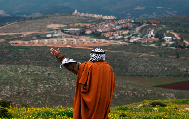 Abdullah Haj Mohammad, the head of Jalud village's council, stands in front of the Jewish settlement unit of Shvut Rachel as he speaks during a tour organised by the Palestinian authorities for ambassadors based in Tel Aviv and consuls based in occupied Jerusalem to show the development of Israeli settler units in the occupied West Bank, Thursday (AFP photo)
