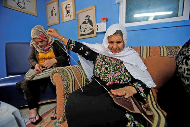 A Palestinian woman makes leather products for sale in a factory in the West Bank town of Dura, south of Hebron, on Sunday (Reuters photo)
