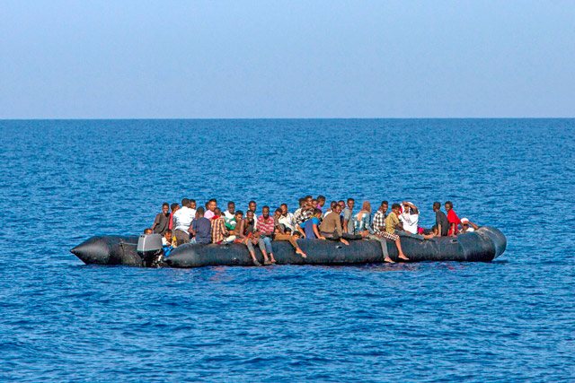 Migrants wait to be rescued by Italian coast guard in the Mediterranean Sea, 55.5km from the Libyan coast, on Sunday (AFP photo)