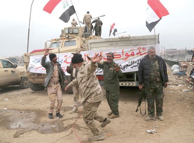 Shiite fighters of the Popular Mobilisation Forces celebrate in a neighbourhood recently liberated from Daesh militants, on the eastern side of Mosul, on Sunday (AP photo)