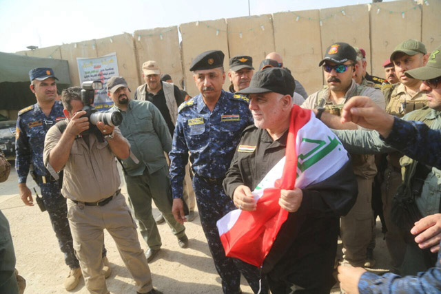 Iraqi Prime Minister Haider Al Abadi (right) holds an Iraqi flag in Mosul, Iraq, on Sunday (Reuters photo)