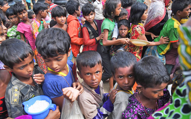 Rohingya refugees wait to receive food distributed by a Turkish aid agency at Thaingkhali refugee camp in Ukhia on Monday (AFP photo)