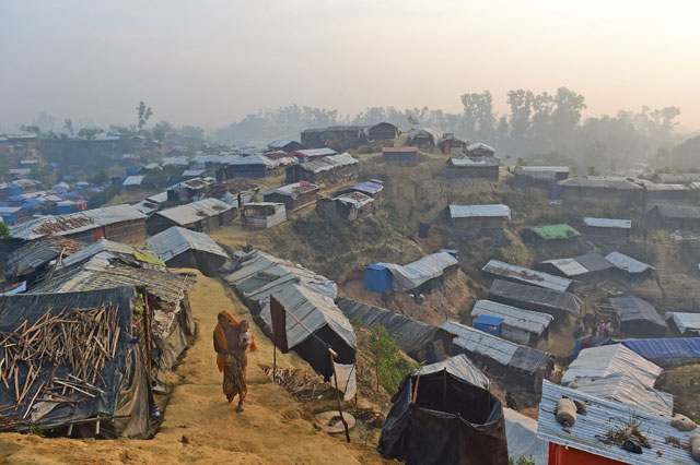 A Rohingya refugee woman walks with a child in her lap in Balukhali refugee camp in the Bangladeshi district of Ukhia on Thursday (AFP photo)