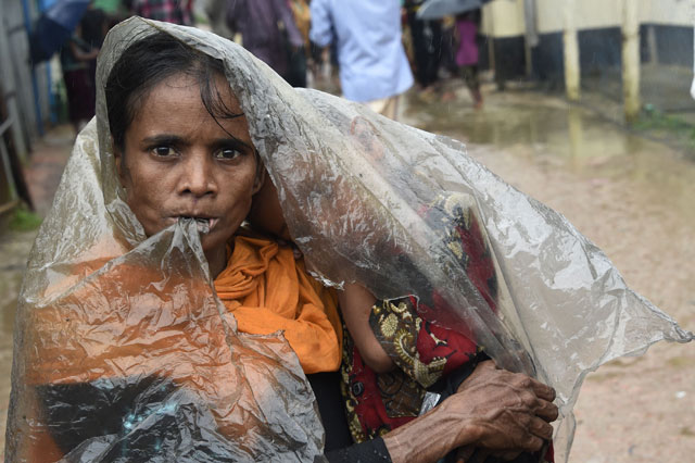 A Rohingya Muslim refugee shelters from the rain at Leda refugee camp near the Bangladeshi district of Teknaf on Tuesday (AFP photo)