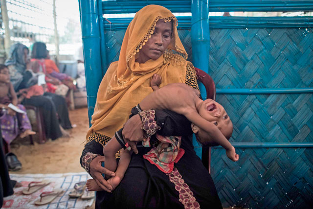 In this photo taken on Sunday, a Rohingya Muslim refugee holds her child as she waits to see a doctor at a medical centre at Balukhali refugee camp near the town of Gumdhum in Cox’s Bazar (AFP photo)