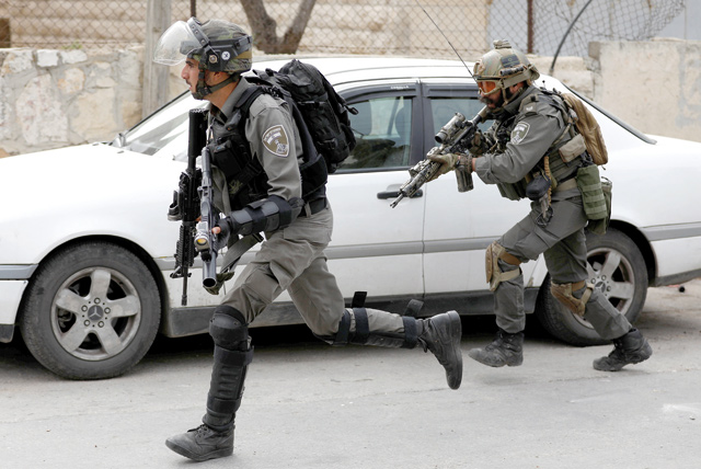 Israeli occupation forces run towards Palestinians during a raid to Al Amari refugee camp in Ramallah in the occupied West Bank, on Monday (Reuters photo)