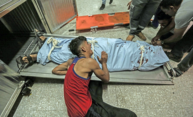 The brother of Sabri Abu Khadir 24, mourns over his body at the morgue of Al Shifa Hospital in Gaza City on Monday (AFP photo)
