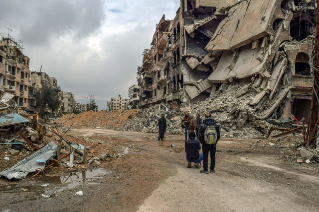 People inspect the debris of buildings after reported government air strikes and ground attacks to Harasta town, in the besieged Eastern Ghouta in Damascus, Syria, on Saturday (Anadolu Agency photo)