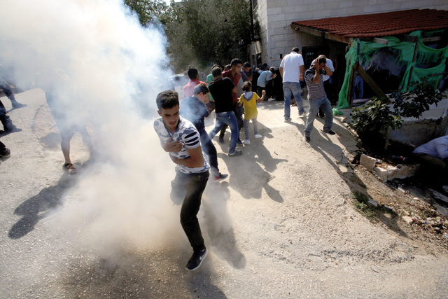 Palestinians react to a sound of grenade fired by Israeli forces as their machineries demolish Palestinian houses in the village of Walajeh near Bethlehem, in the occupied West Bank, on Tuesday  (Reuters photo)