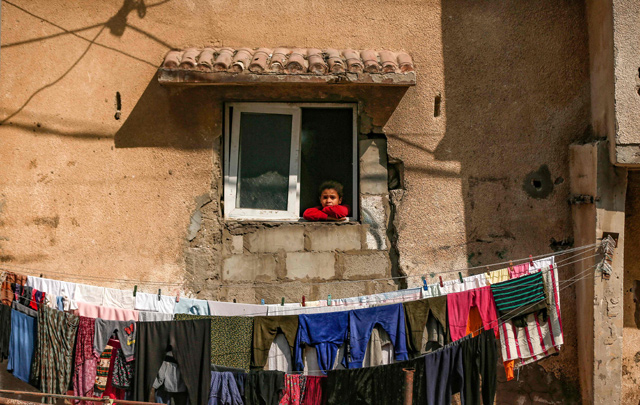 A young member of the Bakr family that lost four children (from extended family), killed during the 2014 Israeli aggression on Gaza, looks out the window of her home in Al Shati refugee camp in Gaza City on Sunday (AFP photo)