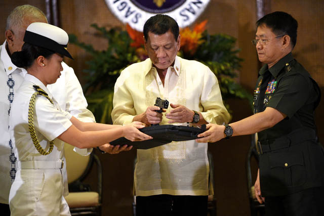 Philippine President Rodrigo Duterte (centre) holds a 45 caliber handgun, one of 3,000 units handed over during a ceremonial turn-over to the military, at Malacanang Palace in Manila, on Tuesday (AFP photo)