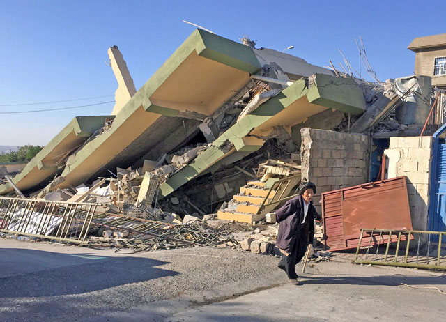A man walks past a damaged building following an earthquake in Darbandikhan in Sulaimaniya Governorate, Iraq, on Monday (Reuters photo)