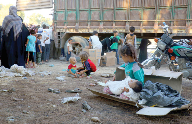 A photo taken on Friday shows displaced Syrian children, who fled from the Daesh group's Syrian stronghold of Raqqa, receiving humanitarian aid delivered by UNICEF at a temporary camp in the town of Tabaqa, about 55 kilometres west of Raqqa (AFP photo)