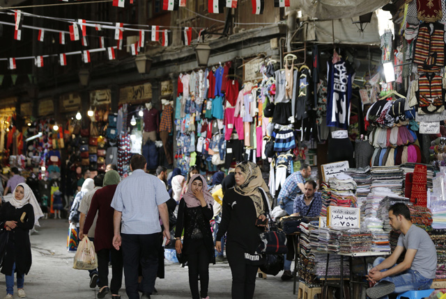 People walk through a shopping district in Old Damascus on Tuesday, one day after the government seized the Yarmouk Palestinian camp and adjacent neighbourhoods of Tadamun and Hajar Al Aswad, putting Damascus fully under its control for the first time since 2012 (AFP photo)