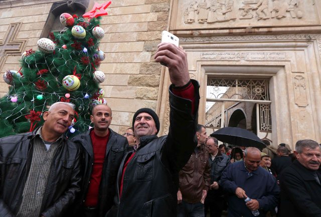 Iraqis take photos with a Christmas tree after attending a Christmas Eve service at the Mar Shimoni Church in the town of Bartalla near Mosul, on Saturday, for the first time since its recapture from the Daesh terror group militants (AFP photo)