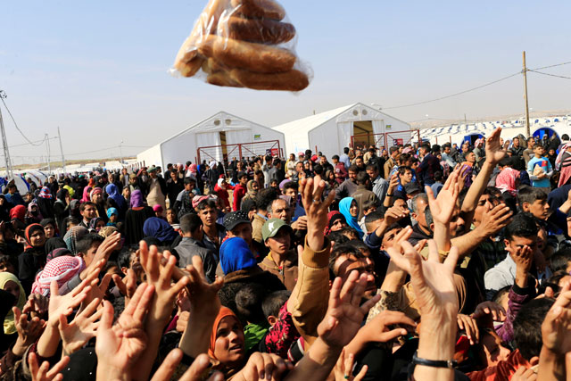 Displaced Iraqi people, who fled from homes during a battle between Iraqi forces and the Daesh militants, receive bread at the Hammam Al Alil camp, south of Mosul, Iraq, on Tuesday (Reuters photo)