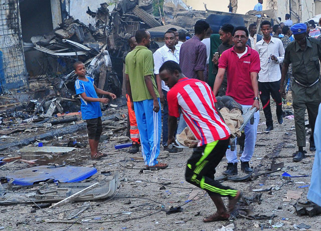 Men carry a body after two car bombs exploded in Mogadishu on Saturday (AFP photo)