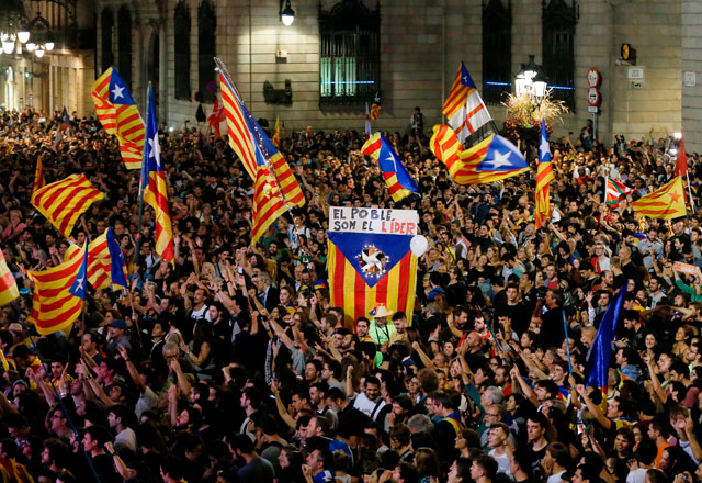 A flag with the text in Catalan ‘The people lead’ is held up as people gather to celebrate the proclamation of a Catalan republic at the Sant Jaume Square in Barcelona, on Friday (AFP photo)