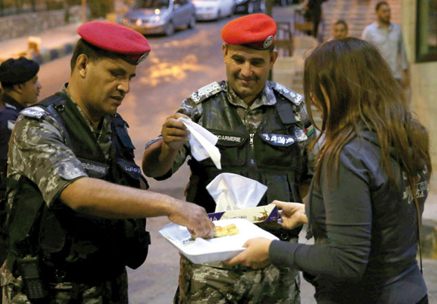 Protesters offer water and dates to policemen standing guard during a protest in Amman on Monday (AFP photo)