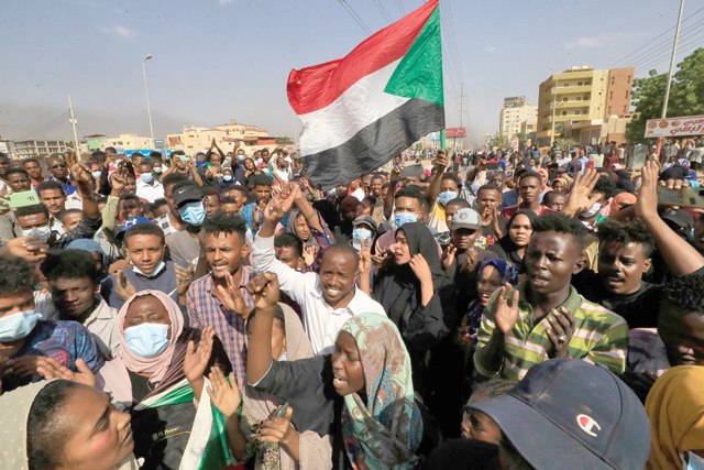 Sudanese protesters carry national flags as they rally on 60th Street in the capital Khartoum, to denounce overnight detentions by the army of government members, on Monday (AFP photo)