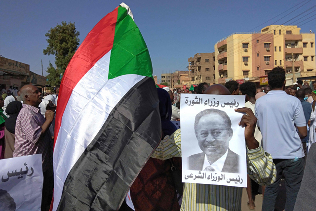 A Sudanese anti-coup protester holds a placard depicting ousted Prime Minister Abdalla Hamdok, who was under house arrest, and reading 'legitimate prime minister' amid ongoing protests against last month's widely condemned military takeover in the 'Street 40' of the capital's twin city of Umdurman on November 17 (AFP photo)