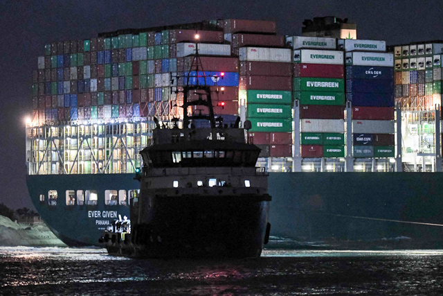 This photo taken late on Saturday shows a view of a tugboat by the Panama-flagged MV 'Ever Given' container ship, which has been wedged diagonally across the span of the canal about six kilometres north of the Suez Canal's entrance by the Red Sea port city of Suez since March 23, blocking the waterway in both directions (AFP photo)