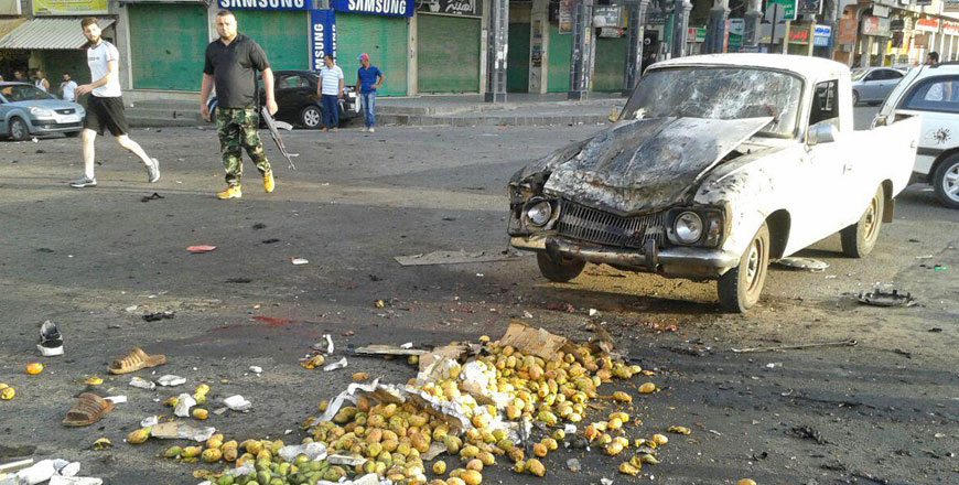 This handout photo released by the official Syrian Arab News Agency on Wednesday shows a member of the Syrian security forces walking past a truck damaged in a suicide attack in the southern city of Sweida (AFP photo)