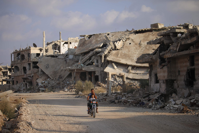This photo taken on Thursday shows a man riding a motorcycle past destroyed buildings in the opposition-held southern Syrian city of Daraa. Syrian forces are close to reinstalling the government’s full control over the southern part of the country (AFP photo)