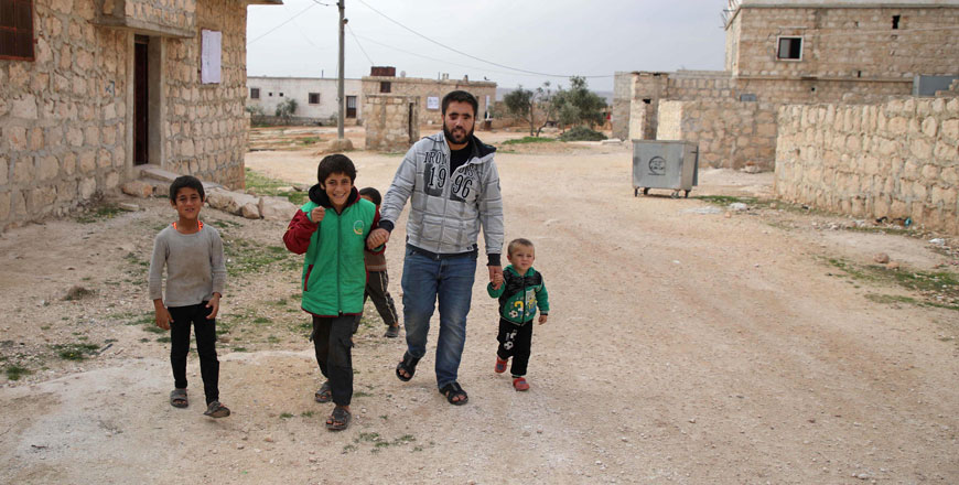 Ahmad Talha, a former Syrian rebel fighter who lost his sight as a result of a gunshot wound, walks with his son (right) and children in the rebel-controlled town of Anjara, in the western Aleppo countryside, on November 10 (AFP photo)