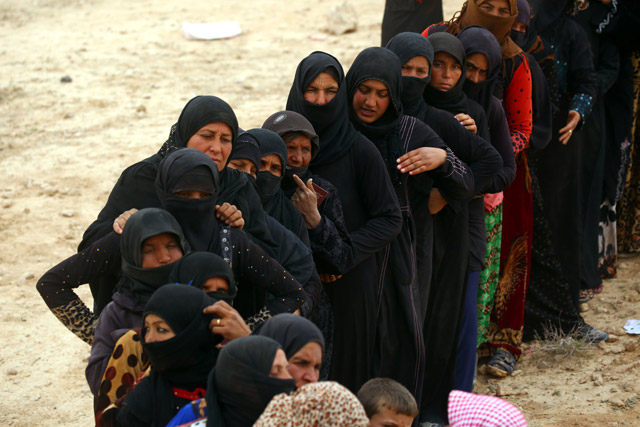 Displaced Syrian women, who fled the countryside surrounding the Daesh terror group stronghold of Raqqa, stand in a queue at a temporary camp in the village of Ain Issa on Friday (AFP photo)
