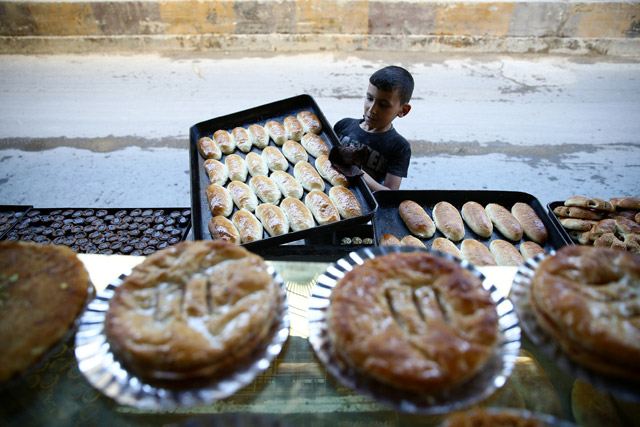 A boy arranges pastries to be sold during Ramadan in the rebel-held besieged eastern Damascus suburb of Ghouta, Syria, on Sunday  (Reuters photo by Bassam Khabieh)