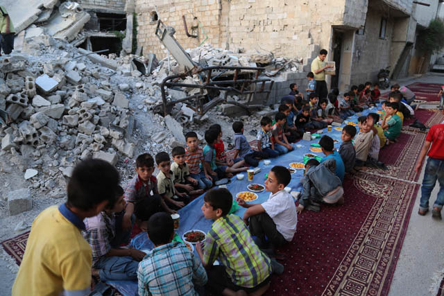 Children attend an iftar dinner organised by Adale Relief Foundation, around the debris of buildings at Duma district during the holy month of Ramadan, in Damascus, Syria, on Tuesday (Anadolu Agency photo)