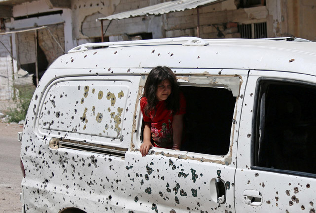 A girl looks out from a bullet-riddled bus in a rebel-held part of the southern city of Daraa, Syria Sunday (Reuters photo)