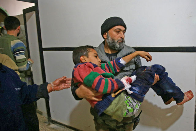 A man carrying a wounded child is seen in Douma Hospital after heavy shelling in the rebel-held besieged town of Douma, eastern Ghouta in Damascus, Syria, on Sunday (Reuters photo)