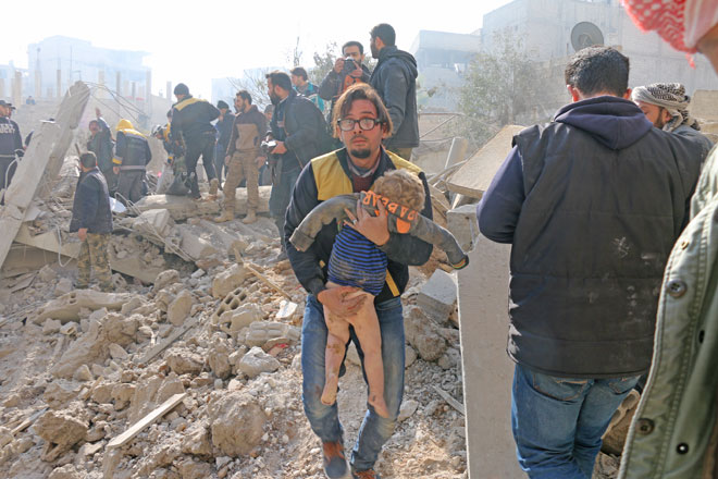 A man carries a wounded kid during the search and rescue operation at the debris of a building after air strikes in the de-escalation zone of Sekba town of Eastern Ghouta in Damascus, Syria, on Tuesday (Anadolu Agency photo)
