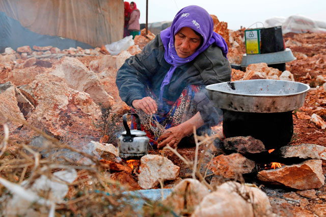A Syrian woman, who fled from the outskirts of southern Idlib due to conflict between government forces and opposition fighters, cooks over a fire at the makeshift camp of Kalbeed near Bab Al Hawa crossing on the Syria-Turkey border on Wednesday (AFP photo)