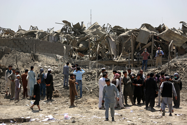 Afghans look at damage caused by a truck bombing in Kabul, Afghanistan, on Monday (AP photo)