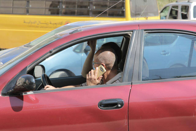 A motorist speaks on the phone while driving in Amman on Sunday (Photo by Osama Aqarbeh)