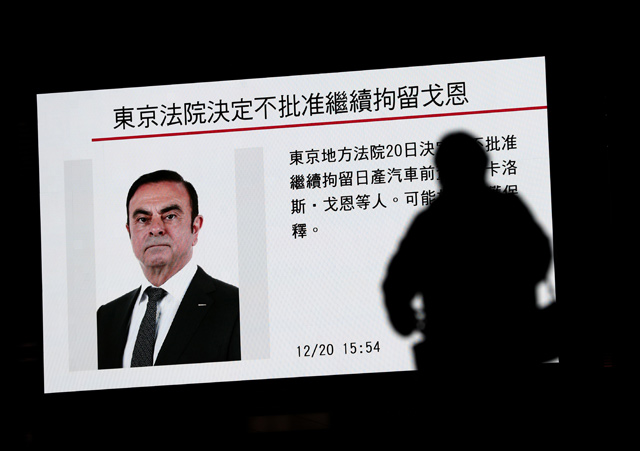 A pedestrian walks past a television screen showing a news programme featuring former Nissan chief Carlos Ghosn in Tokyo on Thursday. Carlos Ghosn could soon be freed on bail after a Japanese court threw out a bid by prosecutors to extend his detention, in a move nearly as unexpected as the auto tycoon's sudden arrest (AFP photo)