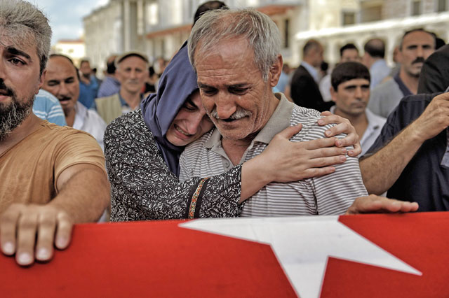 A woman hugs a man as he cries near the flag-draped coffin of a relative as they mourn in Istanbul on Sunday, during the funeral of seven victims of the July 15 coup attempt (AFP photo)