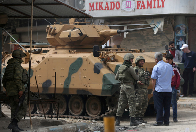 People speak with Turkish soldiers in the centre of Afrin, Syria, on March 24 (Reuters file photo)