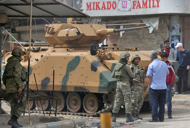 People speak with Turkish soldiers in the centre of Afrin, Syria, on March 24 (Reuters file photo)