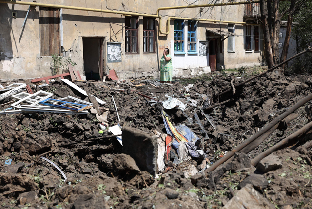 A woman stands in front of her destroyed house following a Russian air strike in the town of Toretske, in the Donetsk region, on Sunday, amid the Russian military invasion of Ukraine (AFP photo)