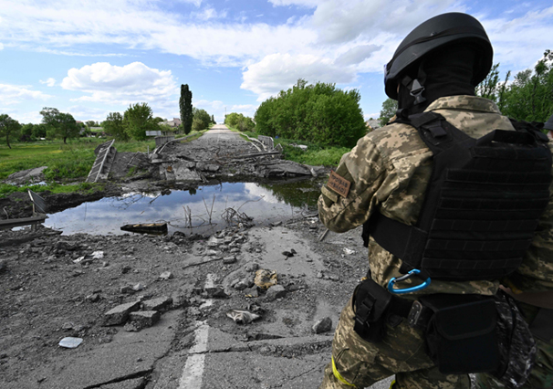 An Ukrainian serviceman stands next to a destroyed bridge near the village of Rus'ka Lozova, north of Kharkiv, on May 28, amid Russian invasion of Ukraine (AFP photo)